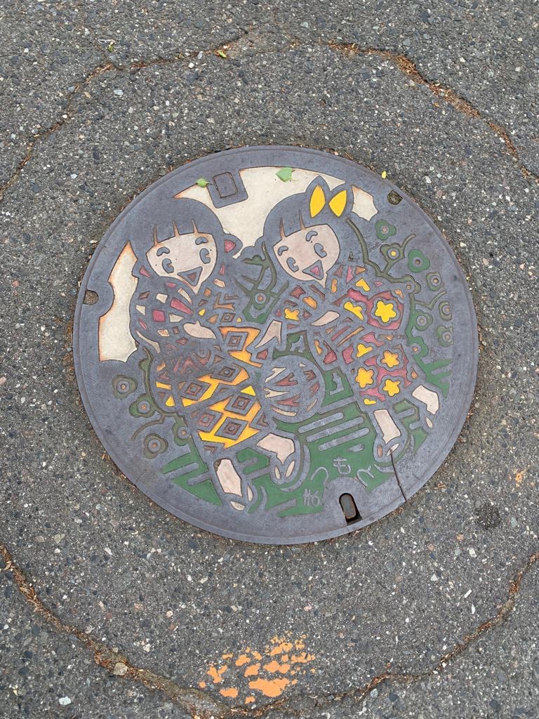 Colorful manhole cover showing two girls in kimonos, Matsumoto